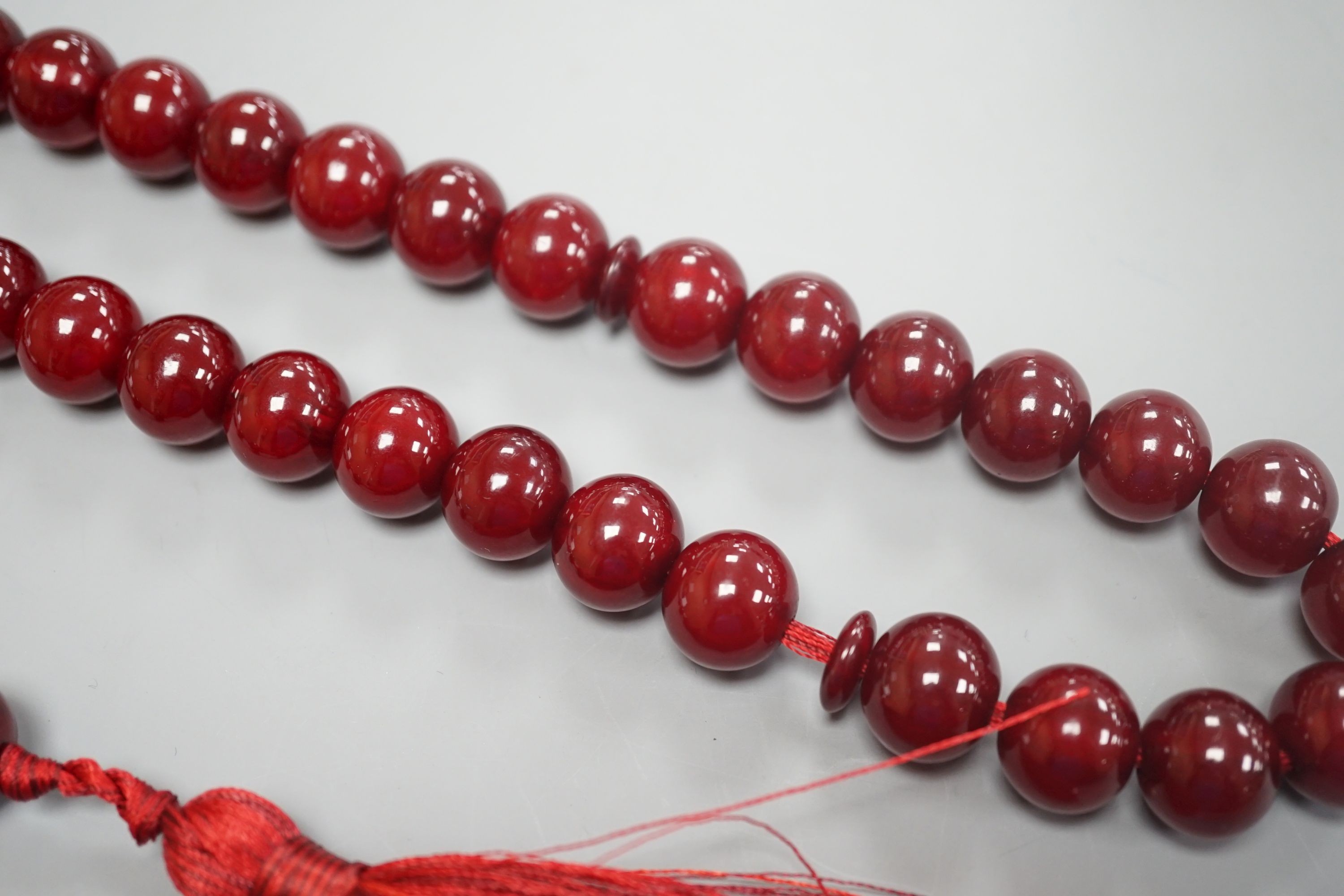 A single strand cherry amber bakelite necklace, 92cm including tassel, gross weight 88 grams.